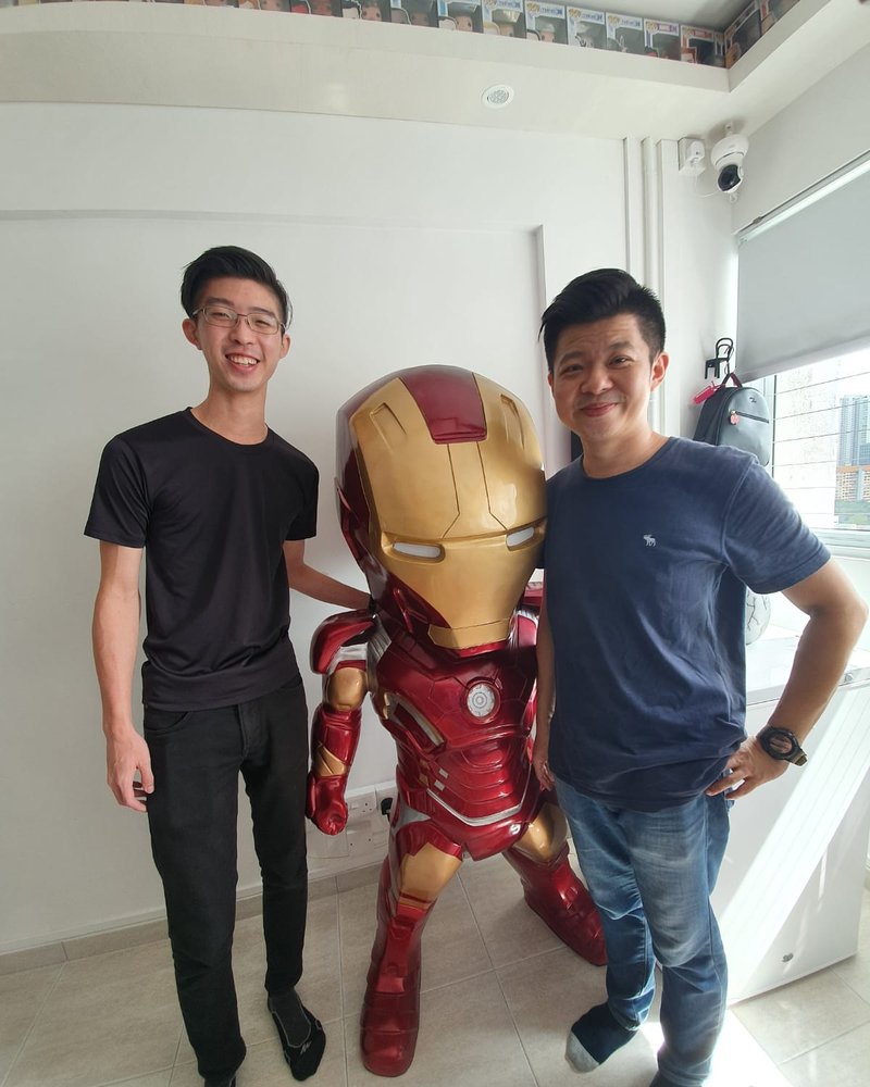 A large fibreglass character statue after full repair and repaint, with the two makers beside it