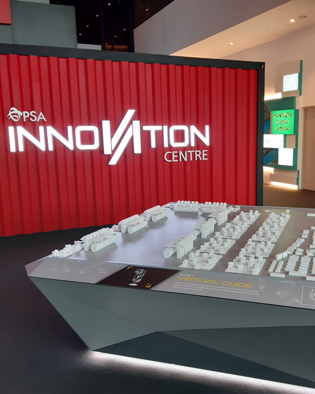 White scale model of Singapore's Tuas mega port displayed beside the red PSA Innovation Centre wall